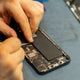 Technician repairing a smartphone battery and internal components.